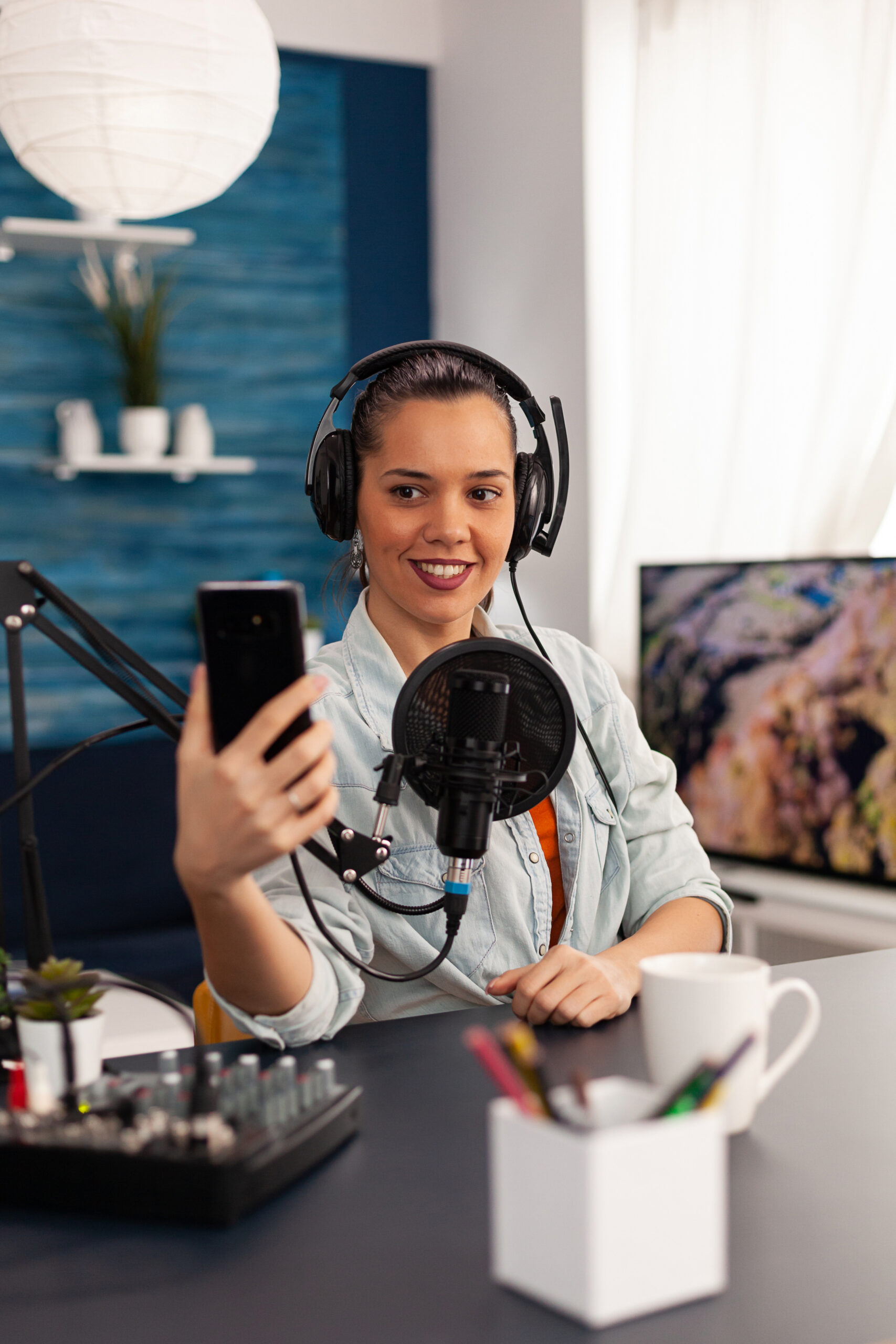 Portrait of blogger woman taking selfie for audience using smartphone working in home studio podcast Portrait of blogger woman taking selfie for audience using smartphone working in podcast home studio. Content creator recording new fashion and beauty review and having fun on social media platform.